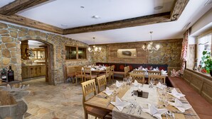 Un espace repas avec des murs en pierre, des meubles en bois et une arche en pierre.