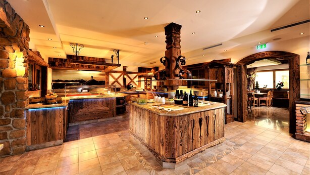 Une cuisine spacieuse dotée d’un grand îlot central en bois, de murs en pierre et d’un éclairage moderne.