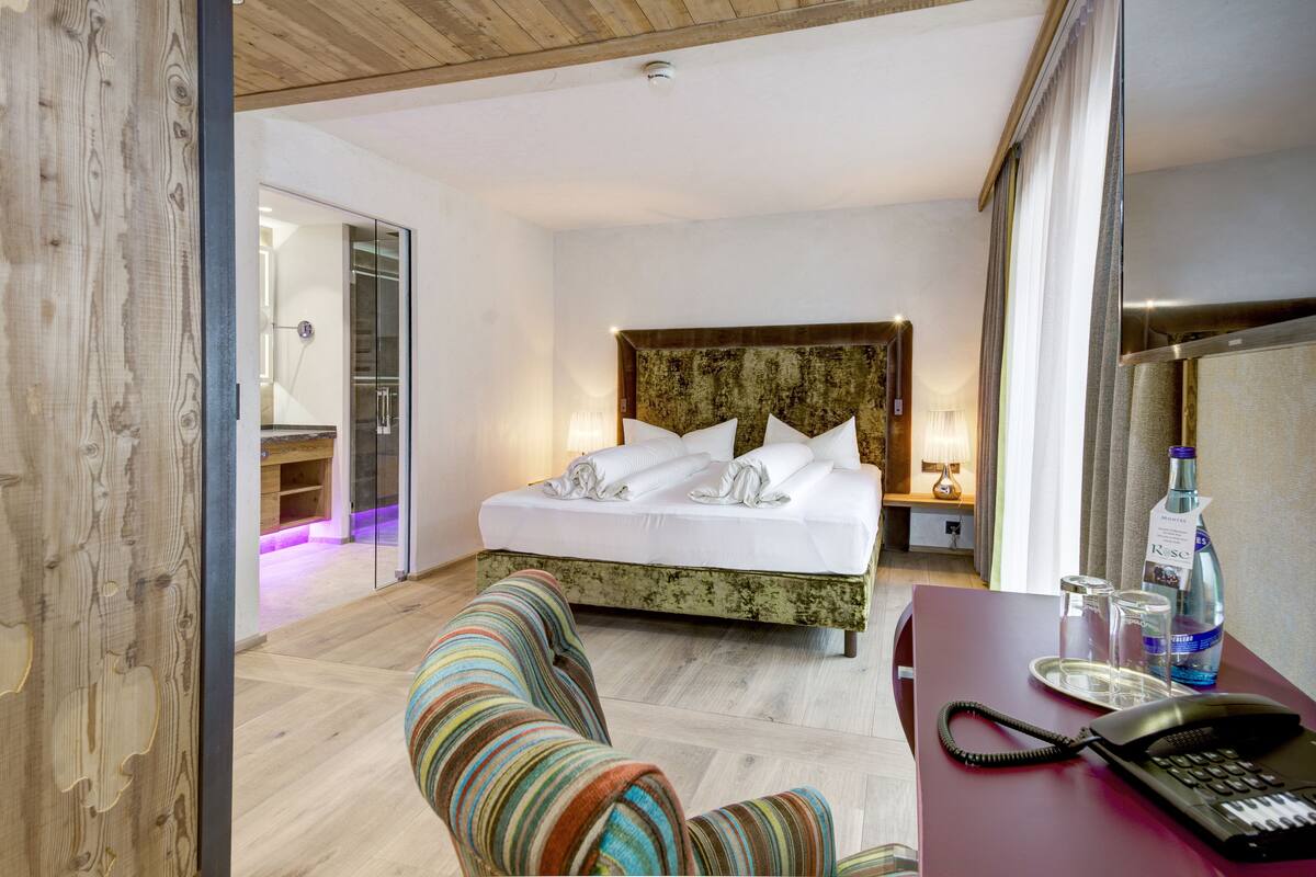 A hotel room with a bed, a desk with a phone, and a chair.
