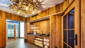 Un intérieur en bois comprenant un comptoir d’accueil, des étagères avec des serviettes et un luminaire original.
