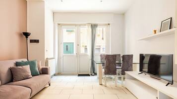 A living room with a sofa, TV, and dining area.