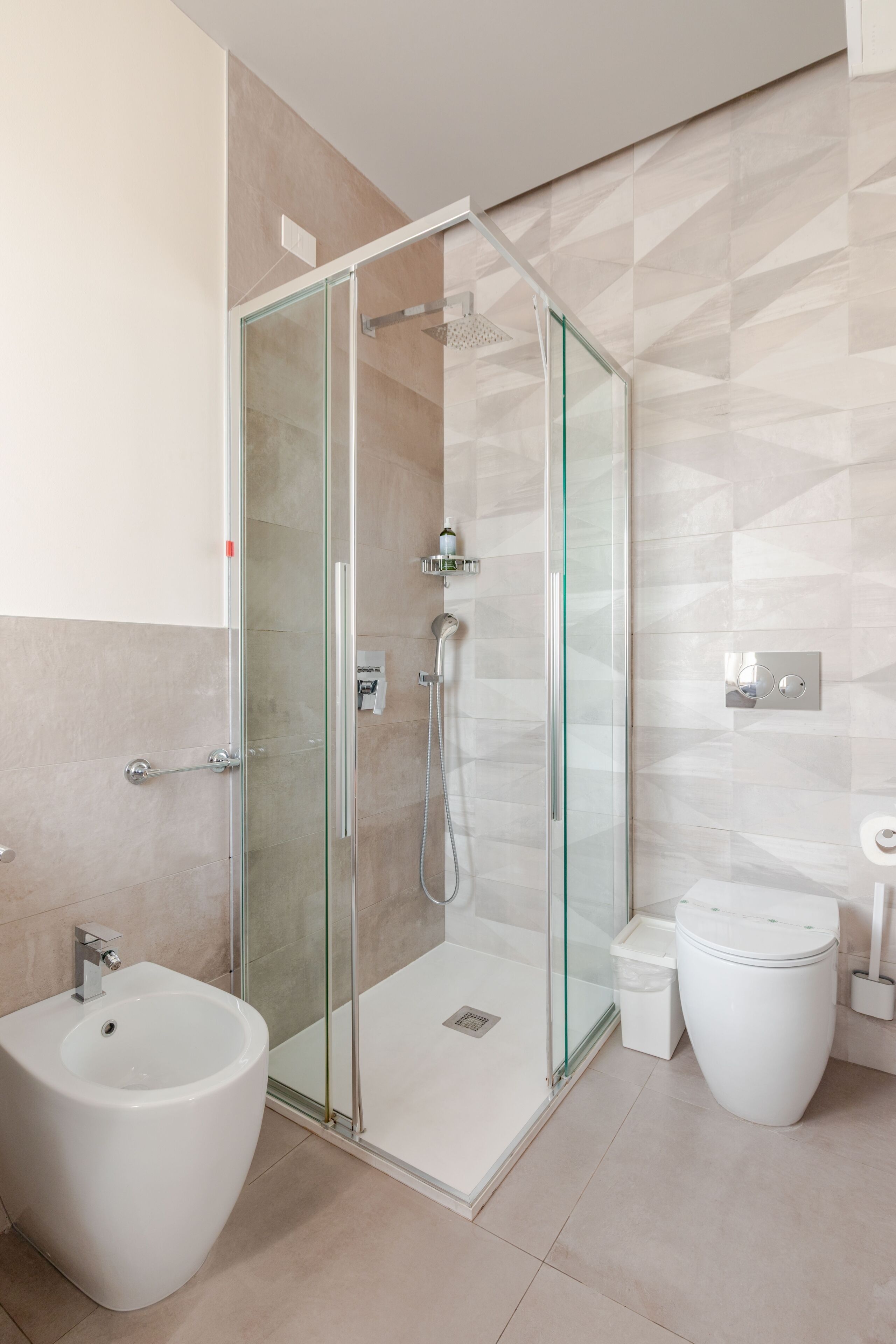 A modern bathroom with a glass-enclosed shower, a white sink, and a toilet.