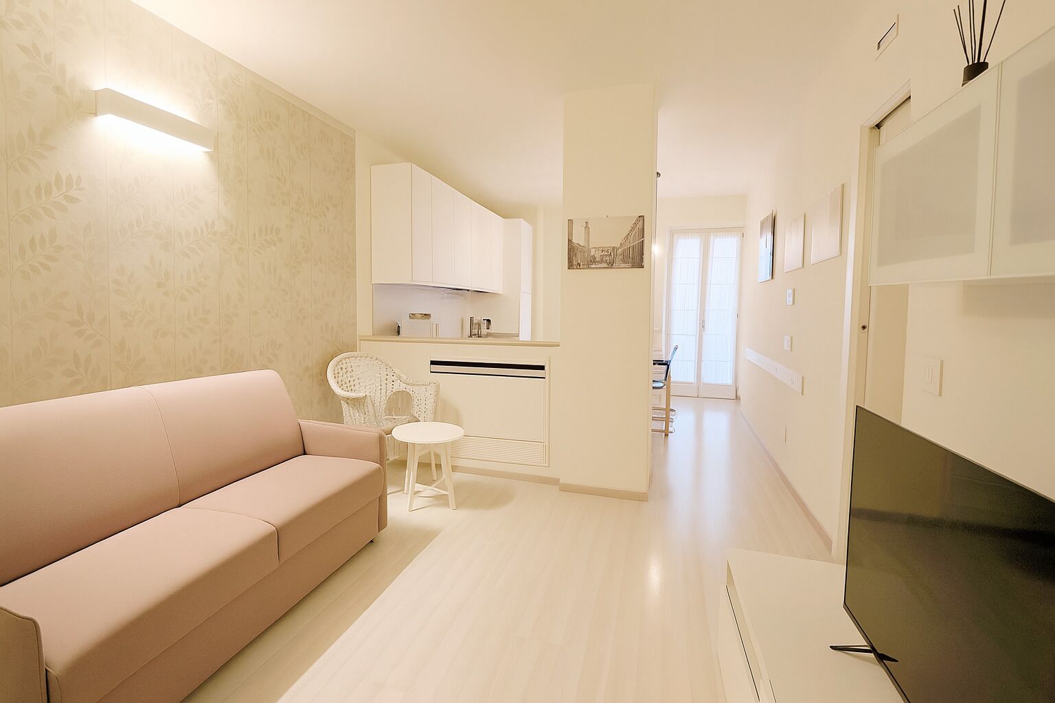 A modern living room with a sofa, a small table, and a TV.