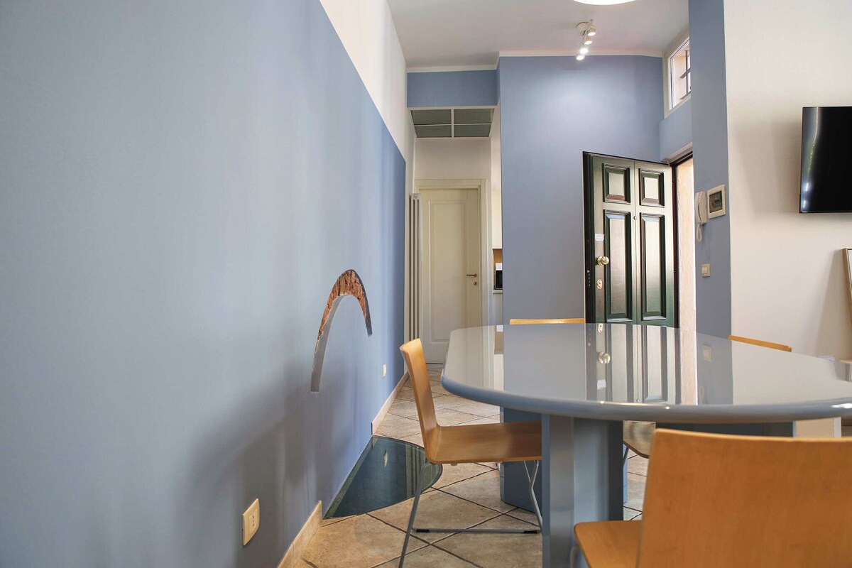 Un comedor con una mesa redonda, sillas y un televisor montado en la pared.
