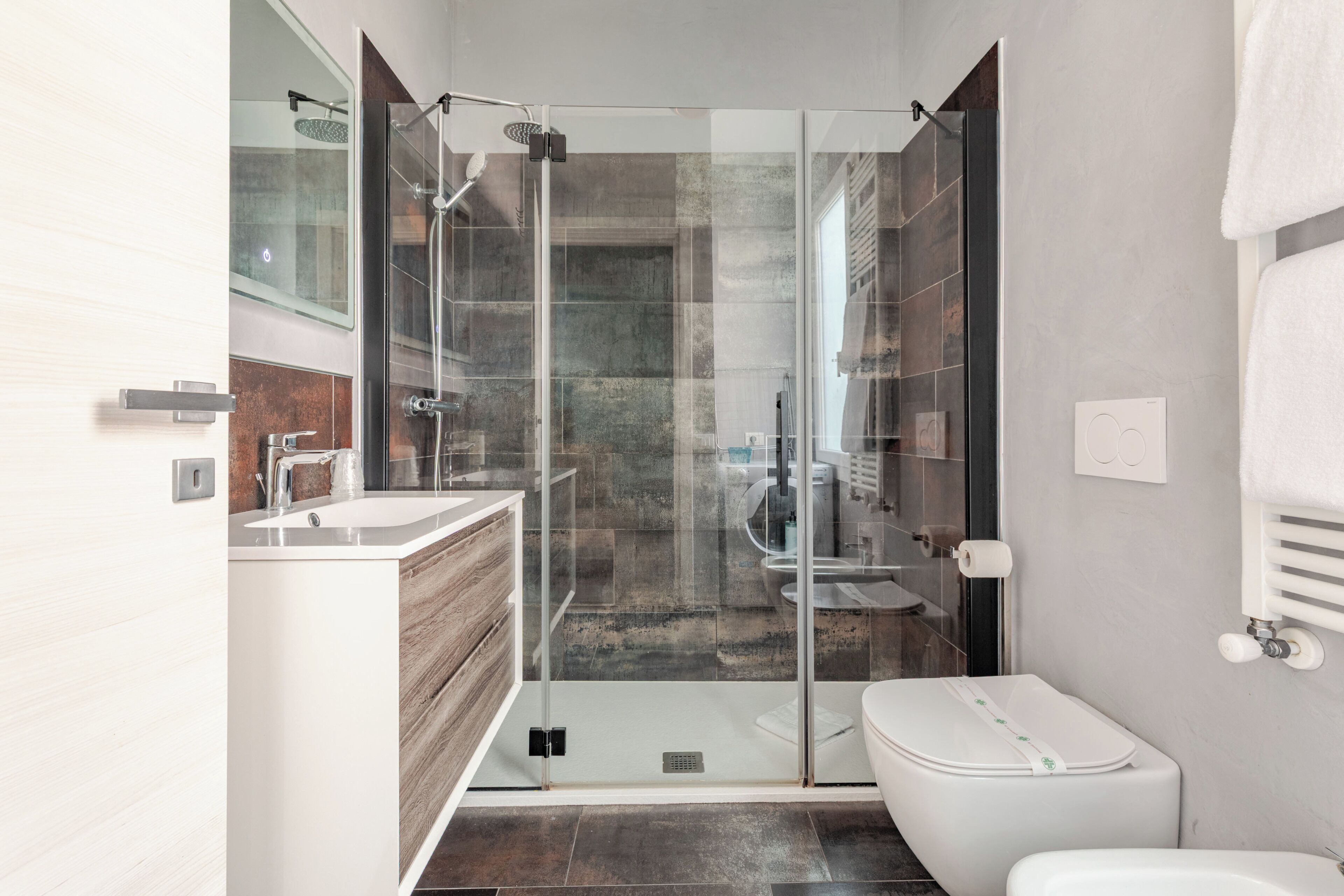 Une salle de bain moderne avec une douche à parois de verre, un lavabo blanc et des toilettes.