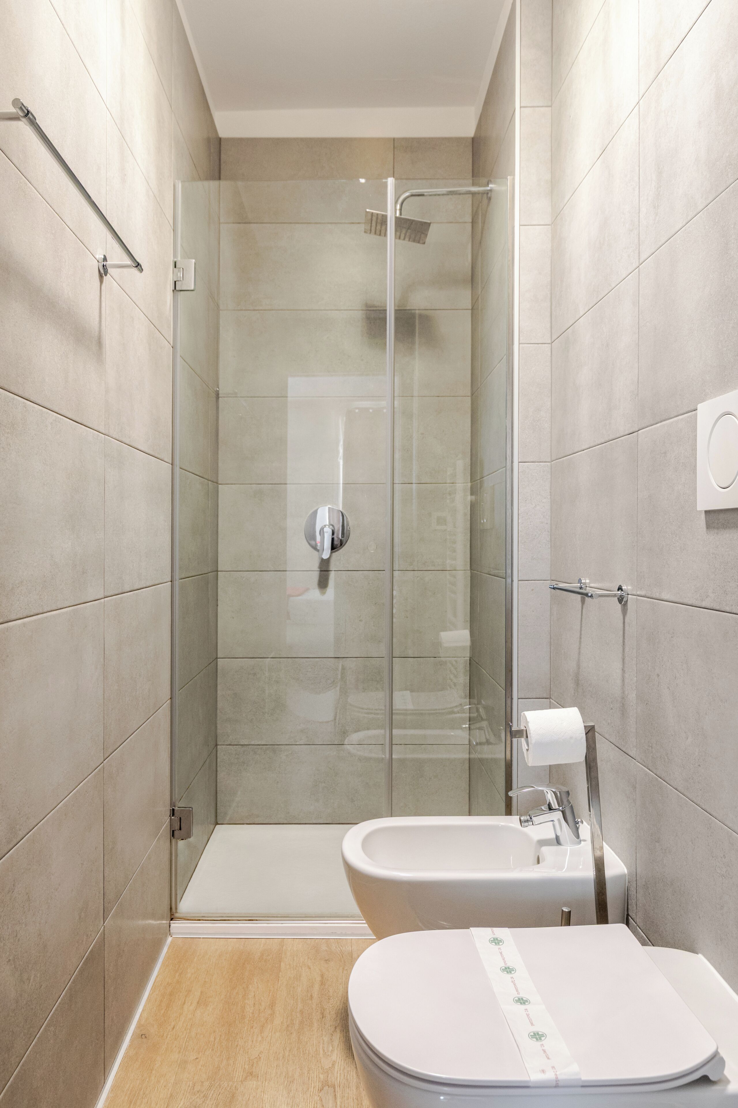 A modern bathroom with a glass-enclosed shower, a toilet, and a bidet.