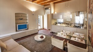 Una sala de estar moderna con una mesa de comedor de cristal, un sofá y un televisor.