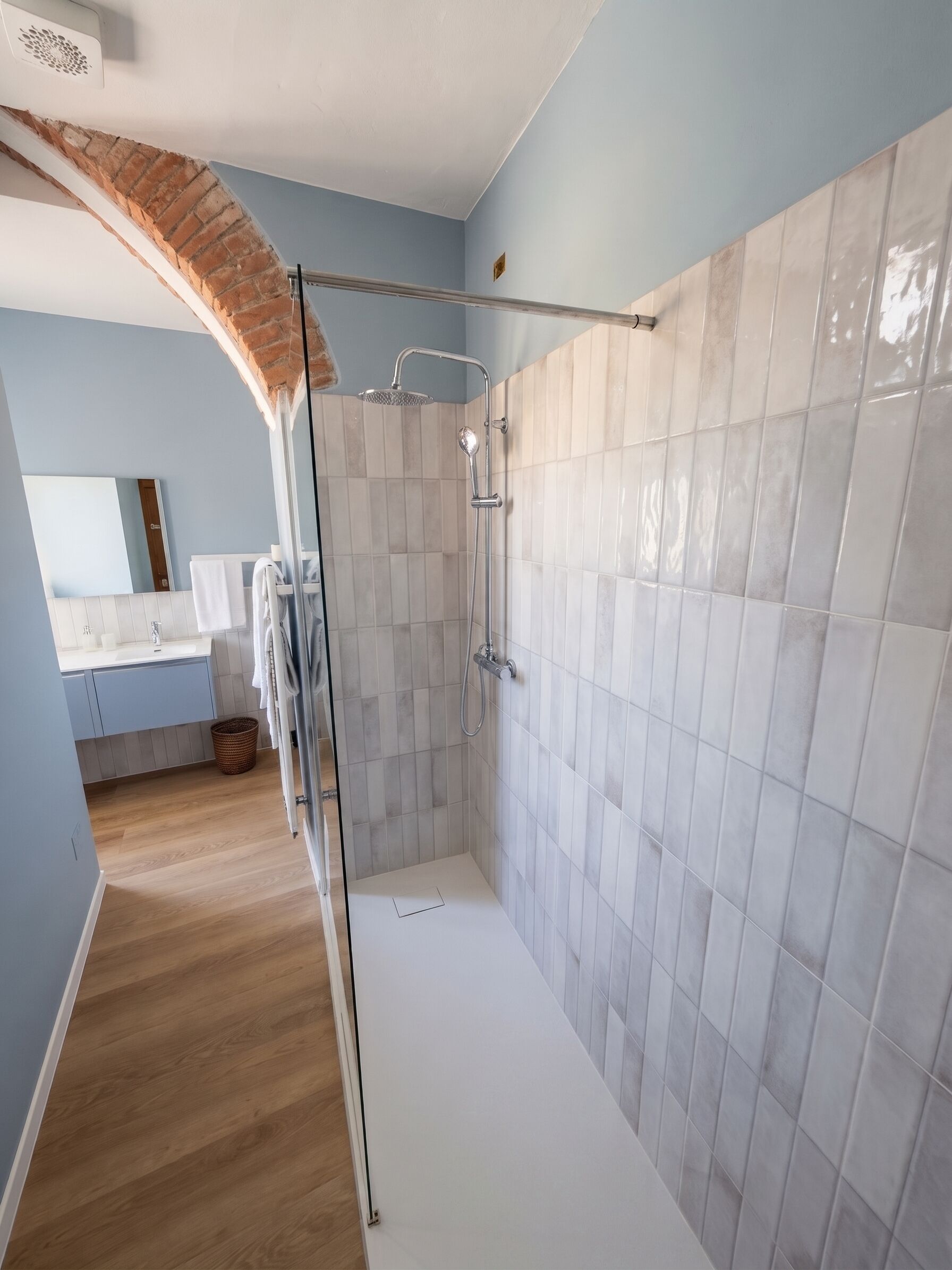 Ein modernes Badezimmer mit Dusche, Glasabtrennung und Holzboden.
