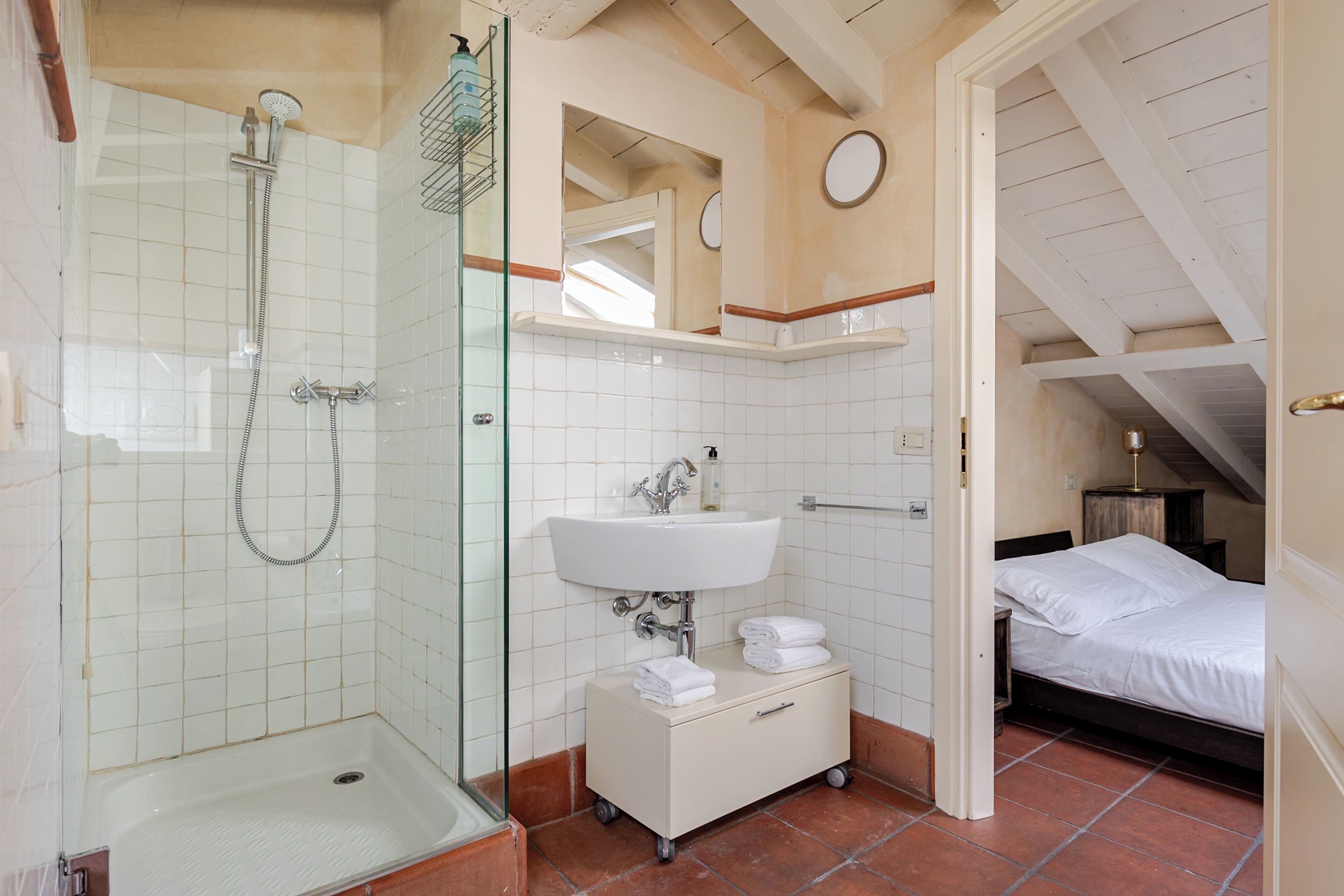 Ein Badezimmer mit Dusche, Waschbecken und einem Nachttisch mit Handtüchern.