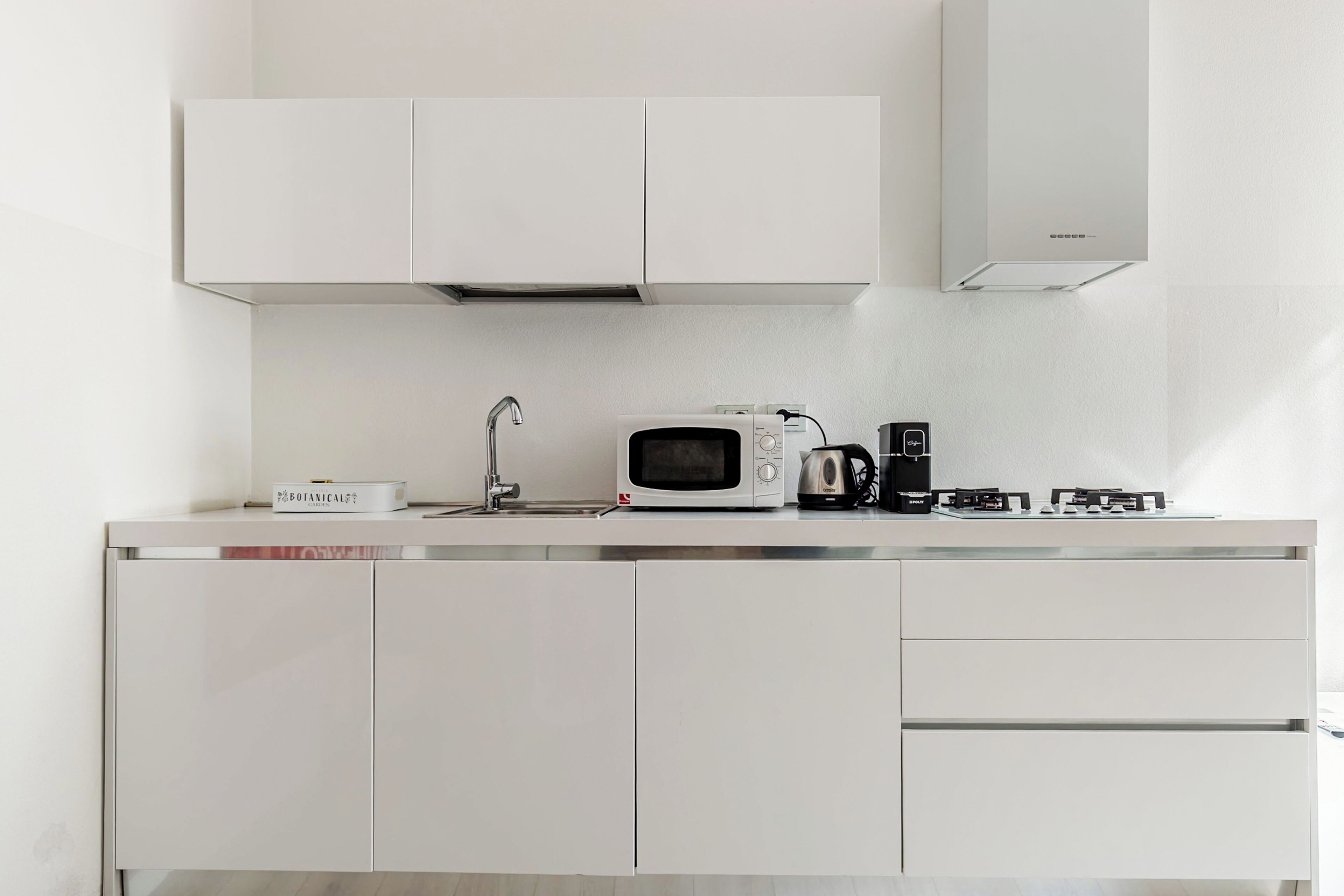 A modern kitchen with a microwave, kettle, and a box labeled 'Botanical'.