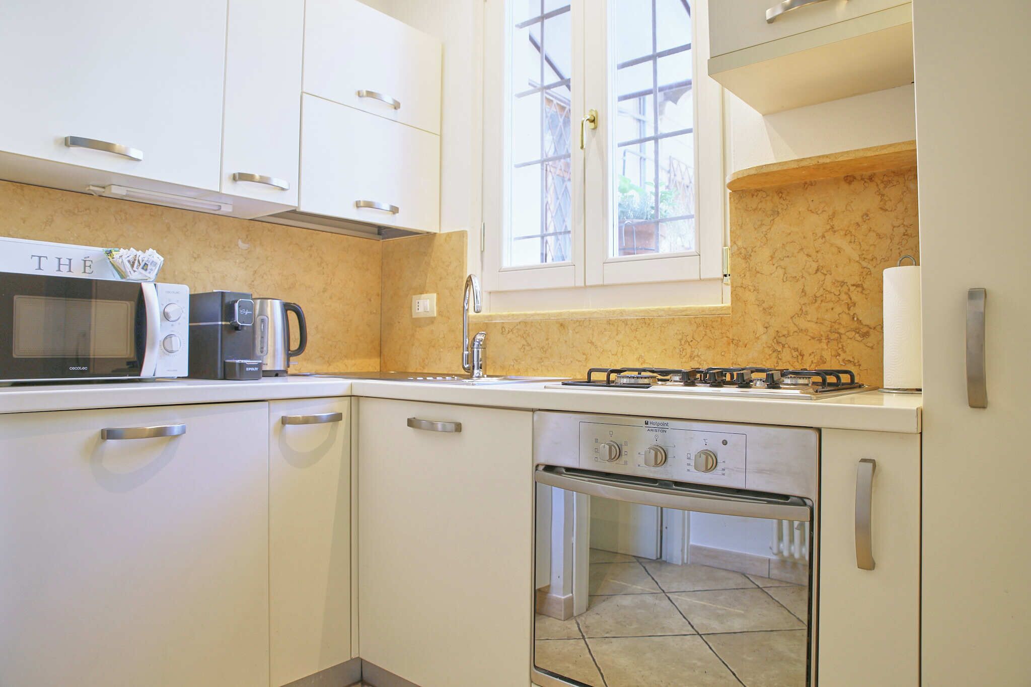 A compact kitchen with a microwave, coffee maker, and gas stove.