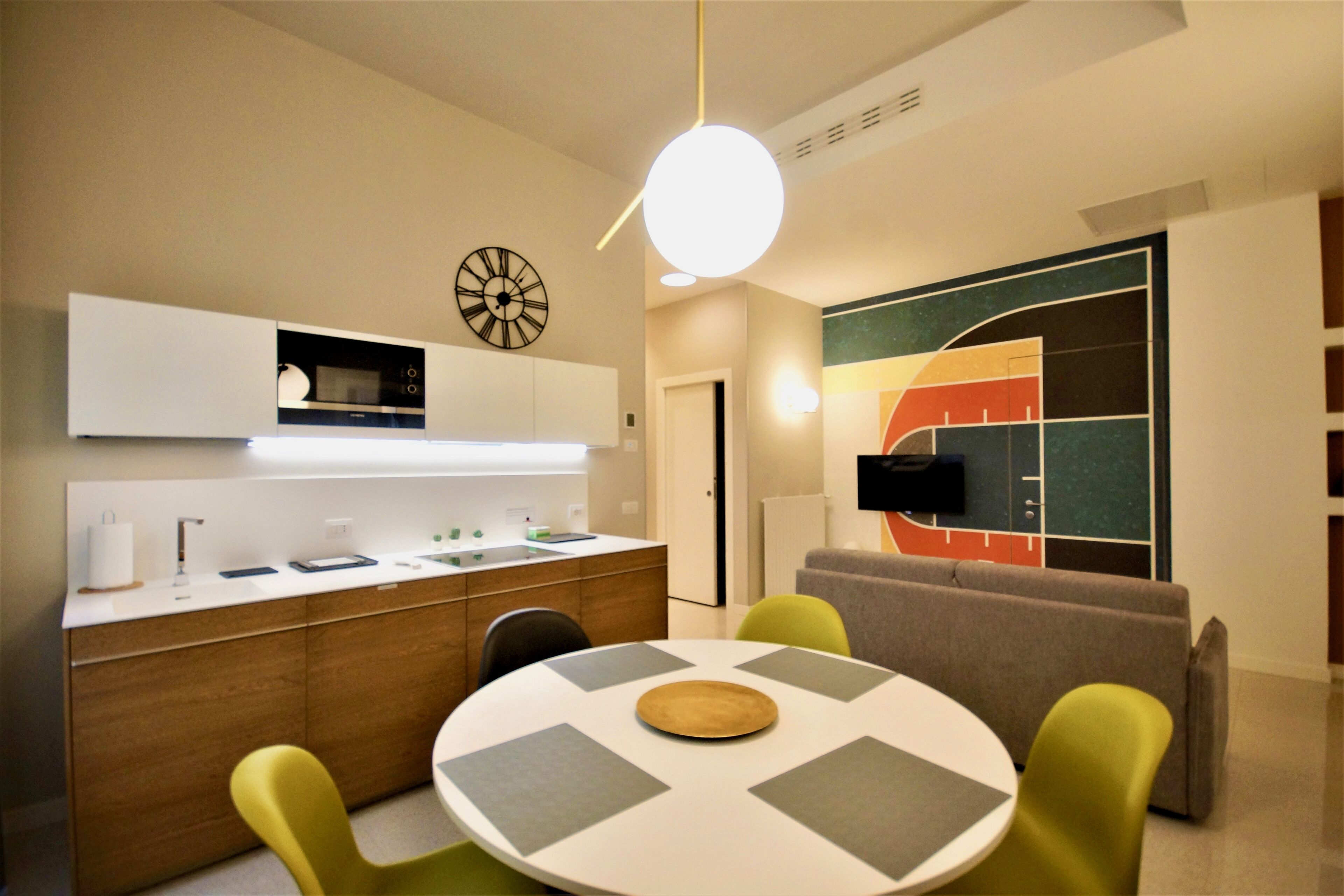 A modern kitchen with a microwave, sink, and cabinets. There is a dining area with a round table and chairs.