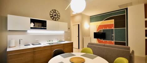 A modern kitchen with a microwave, sink, and cabinets. There is a dining area with a round table and chairs.
