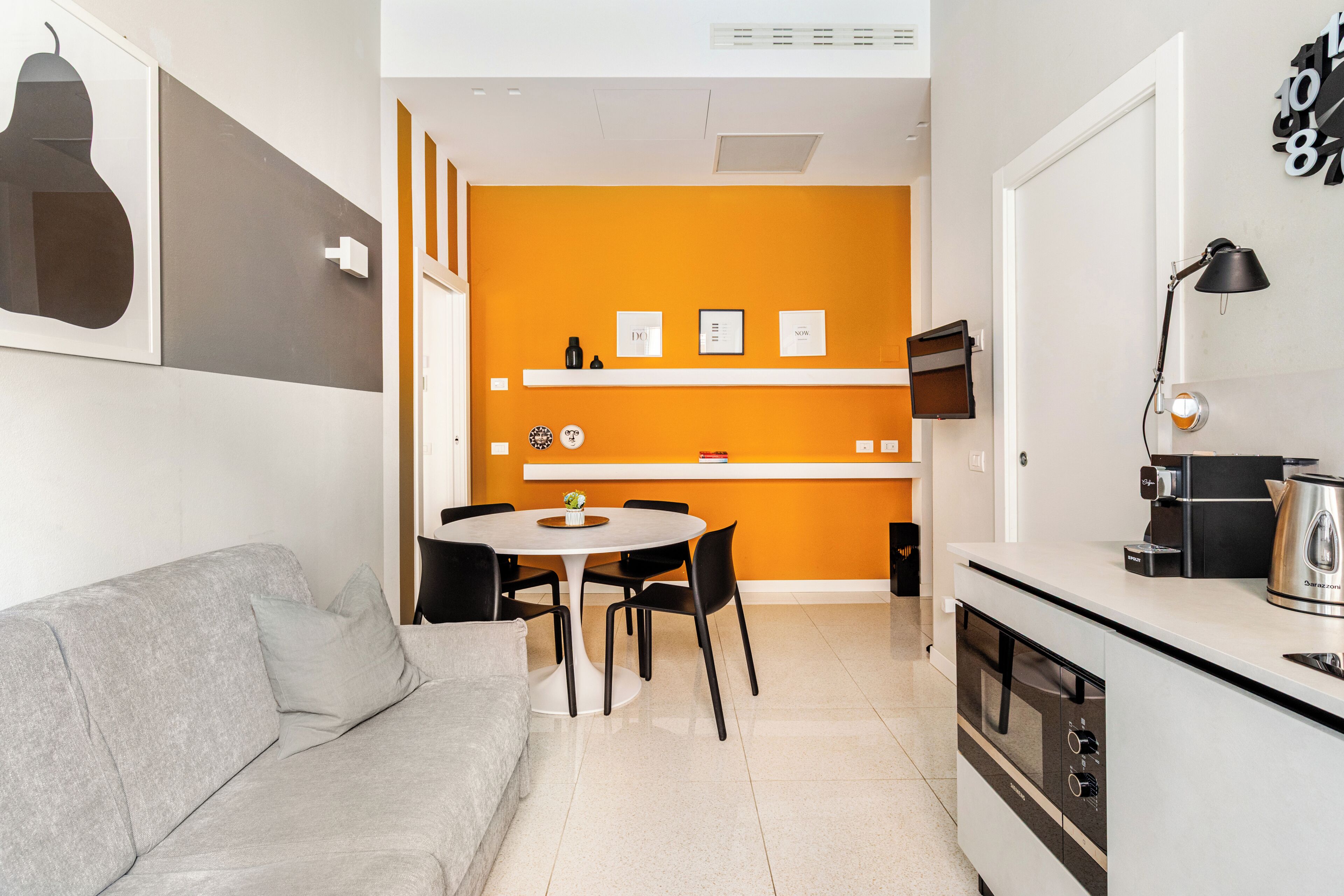 A modern kitchen with a white countertop, a built-in oven, and a coffee machine.