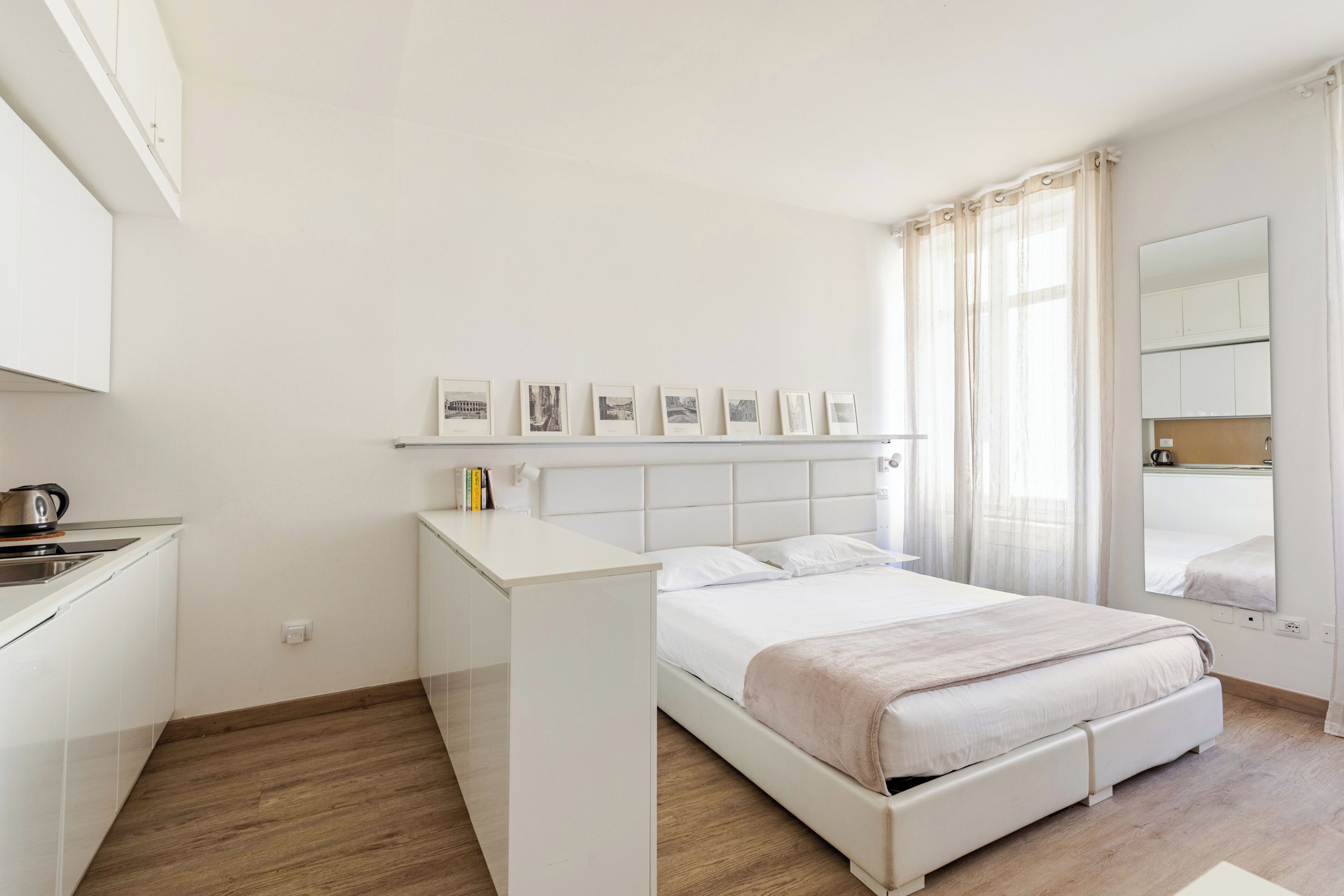 Une chambre avec un lit, une table de chevet et une petite kitchenette.