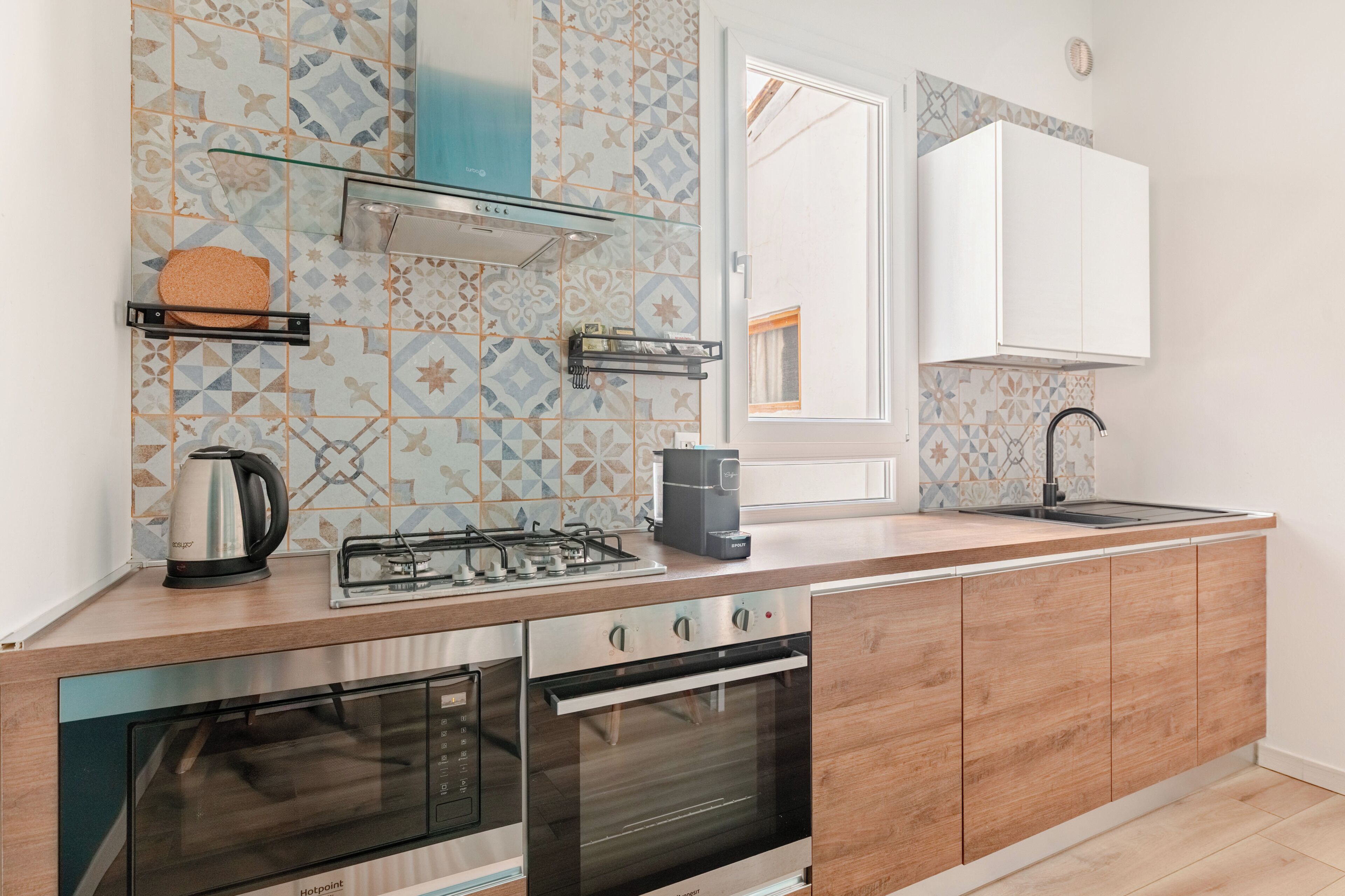 A modern kitchen with a gas stove, oven, and built-in microwave. There is a window with a view of the outside.