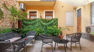 Un patio al aire libre con mobiliario de mimbre, una pared verde y una pared de piedra.