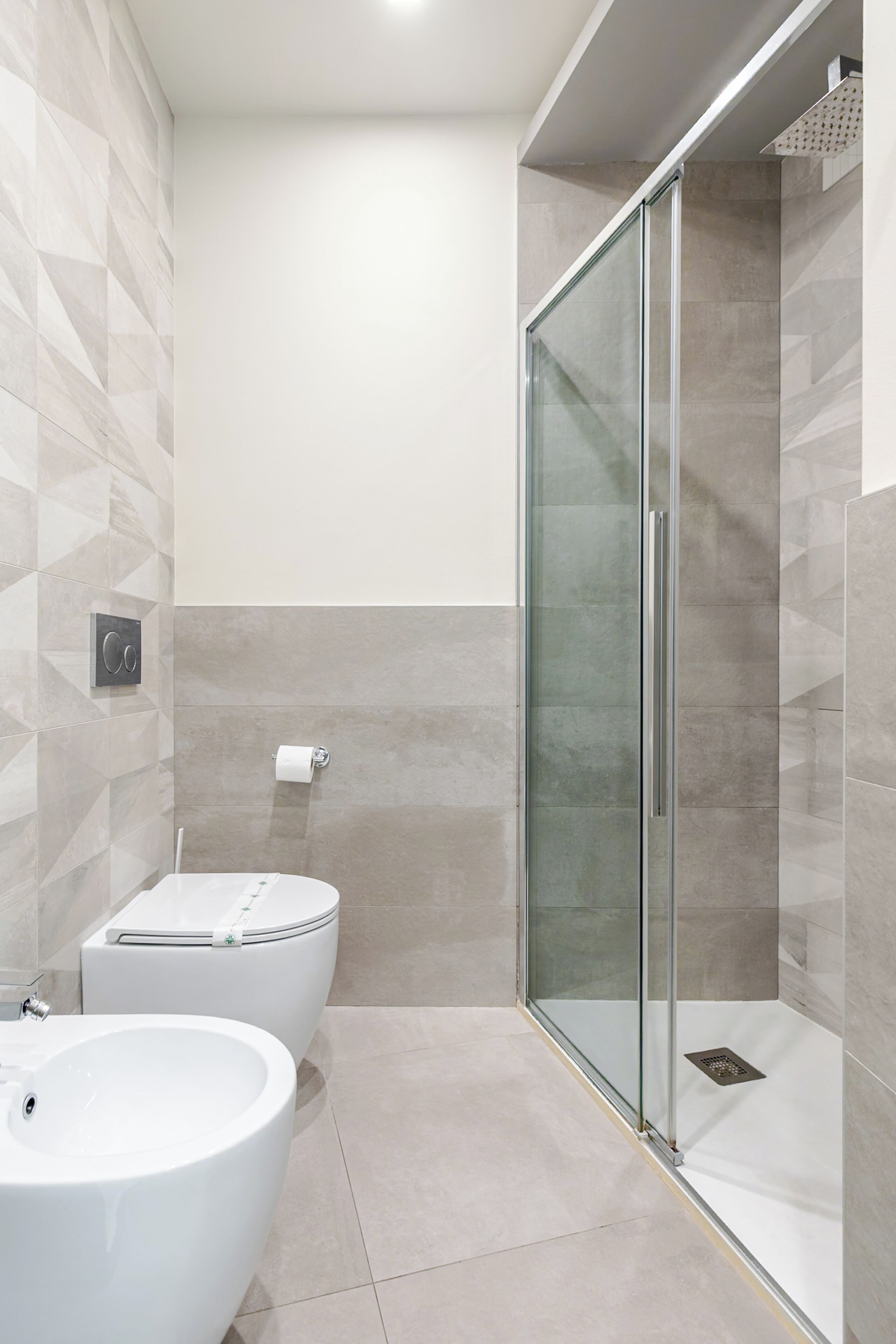 A modern bathroom with a glass-enclosed shower, a white sink, and a toilet.