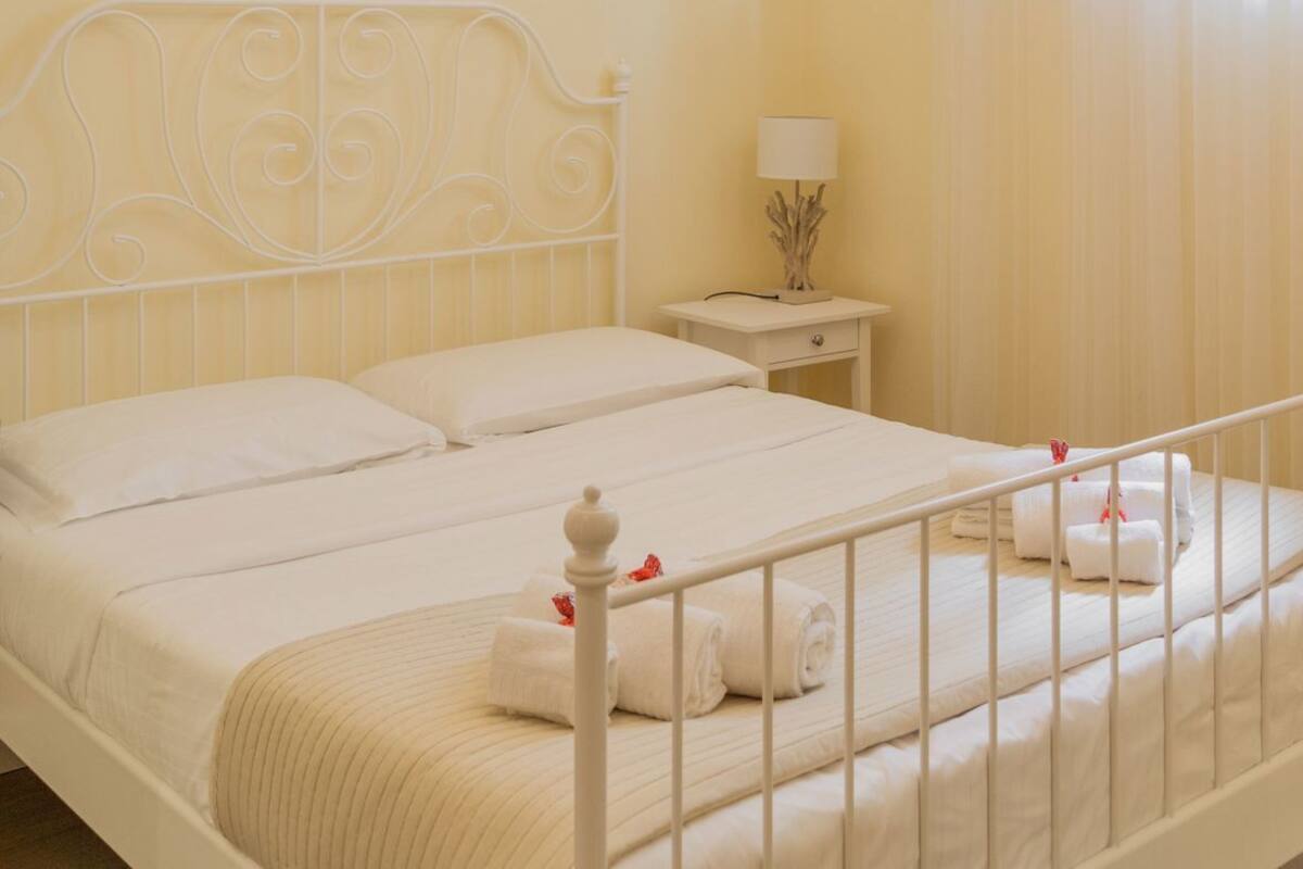 A hotel room with a bed, a nightstand, a lamp, and a chandelier.