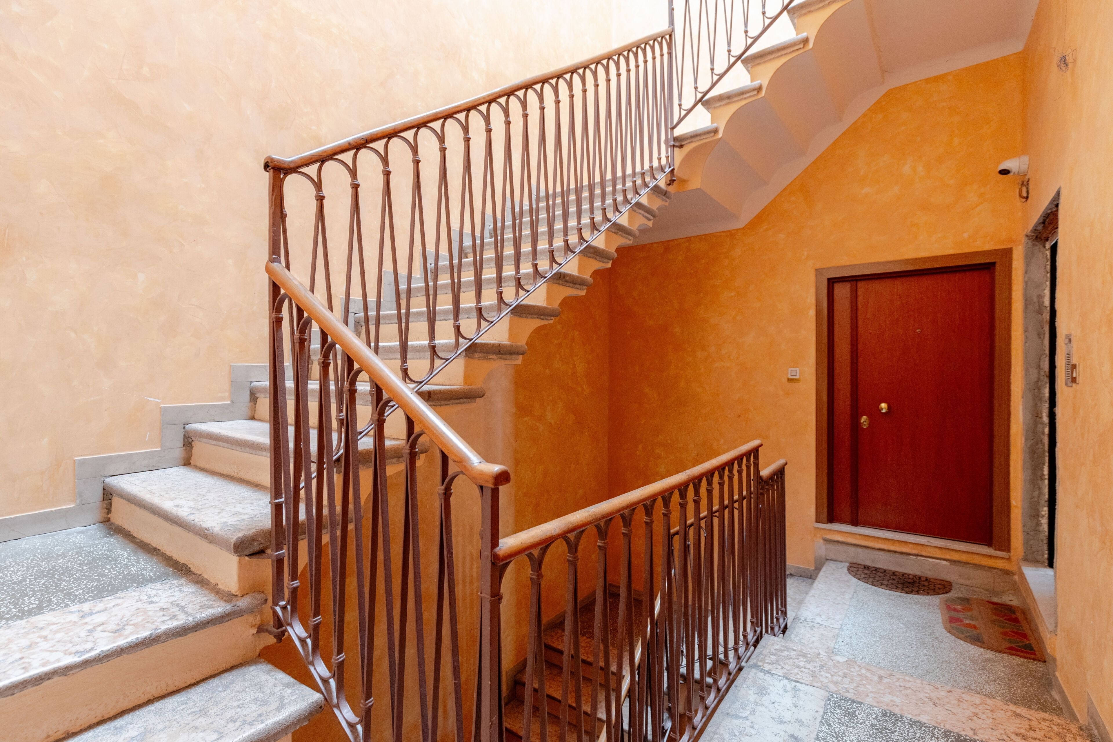 A staircase with metal railings and a red door at the bottom.
