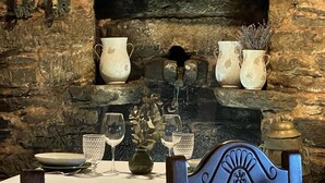 A table set with wine glasses, a vase, and a candle holder against a stone wall backdrop. - Casa Brandariz (Arzua)