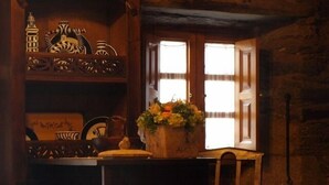 A rustic interior with a wooden table, a chair, and a window with white shutters. - Casa Brandariz (Arzua)