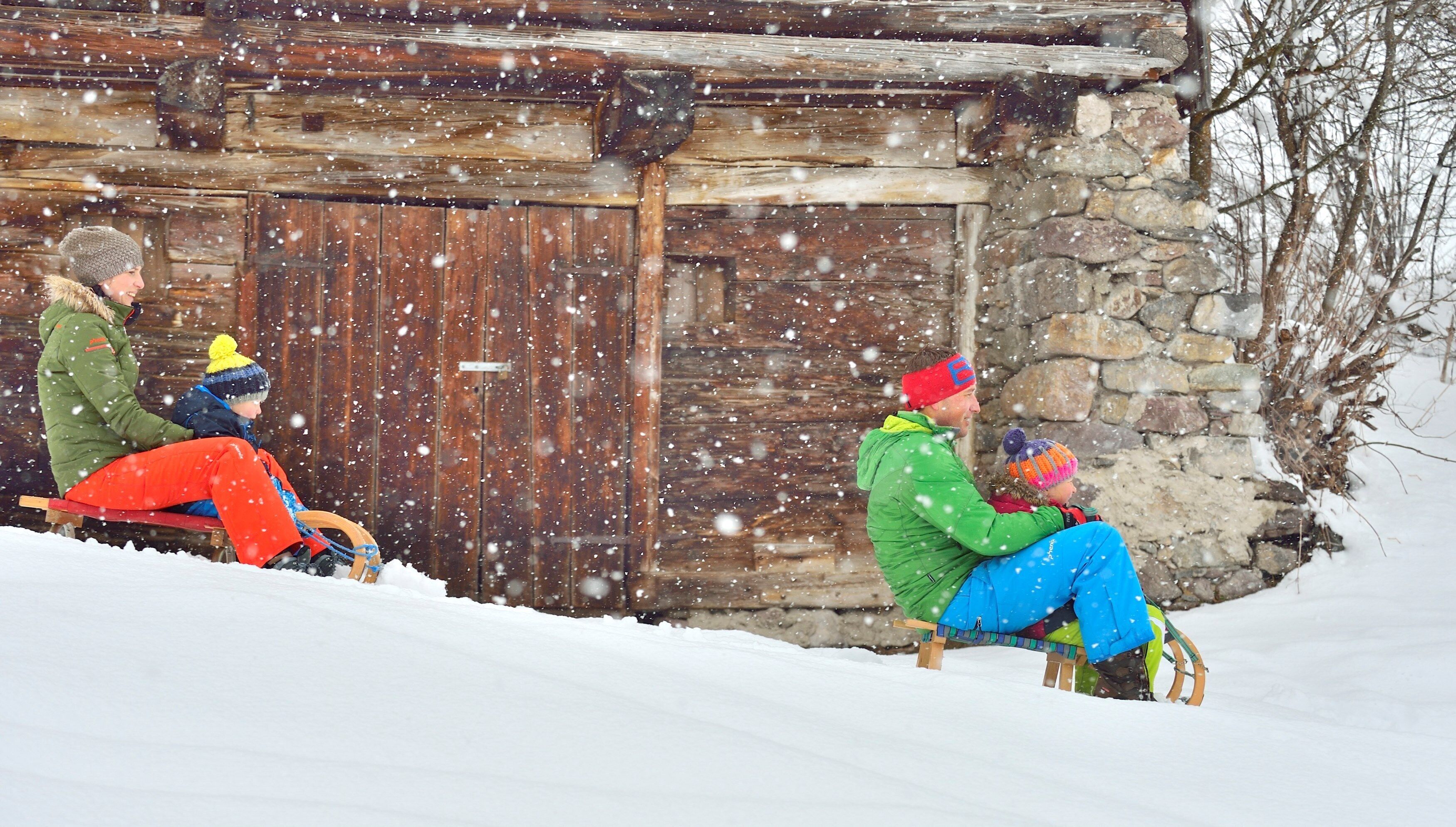A rustic cabin with a wooden door and stone walls, surrounded by snow.