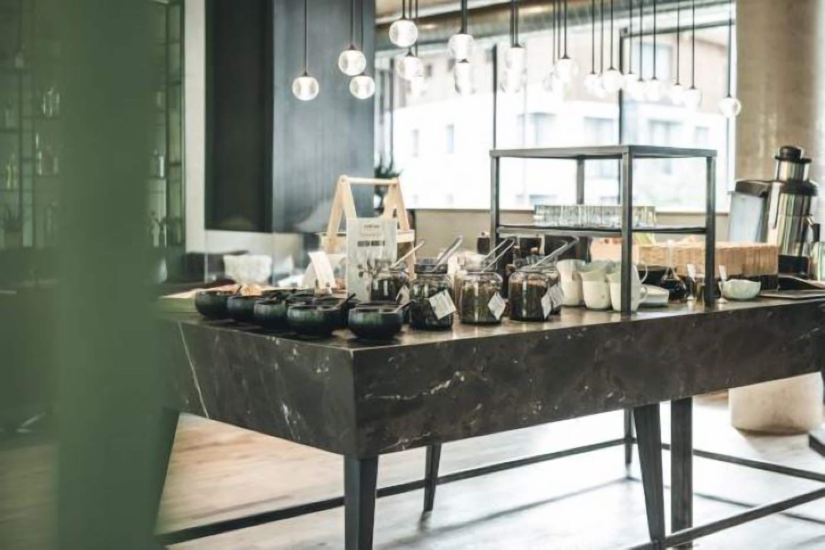 A kitchen counter with various kitchen utensils and appliances, a coffee machine, and hanging light fixtures.