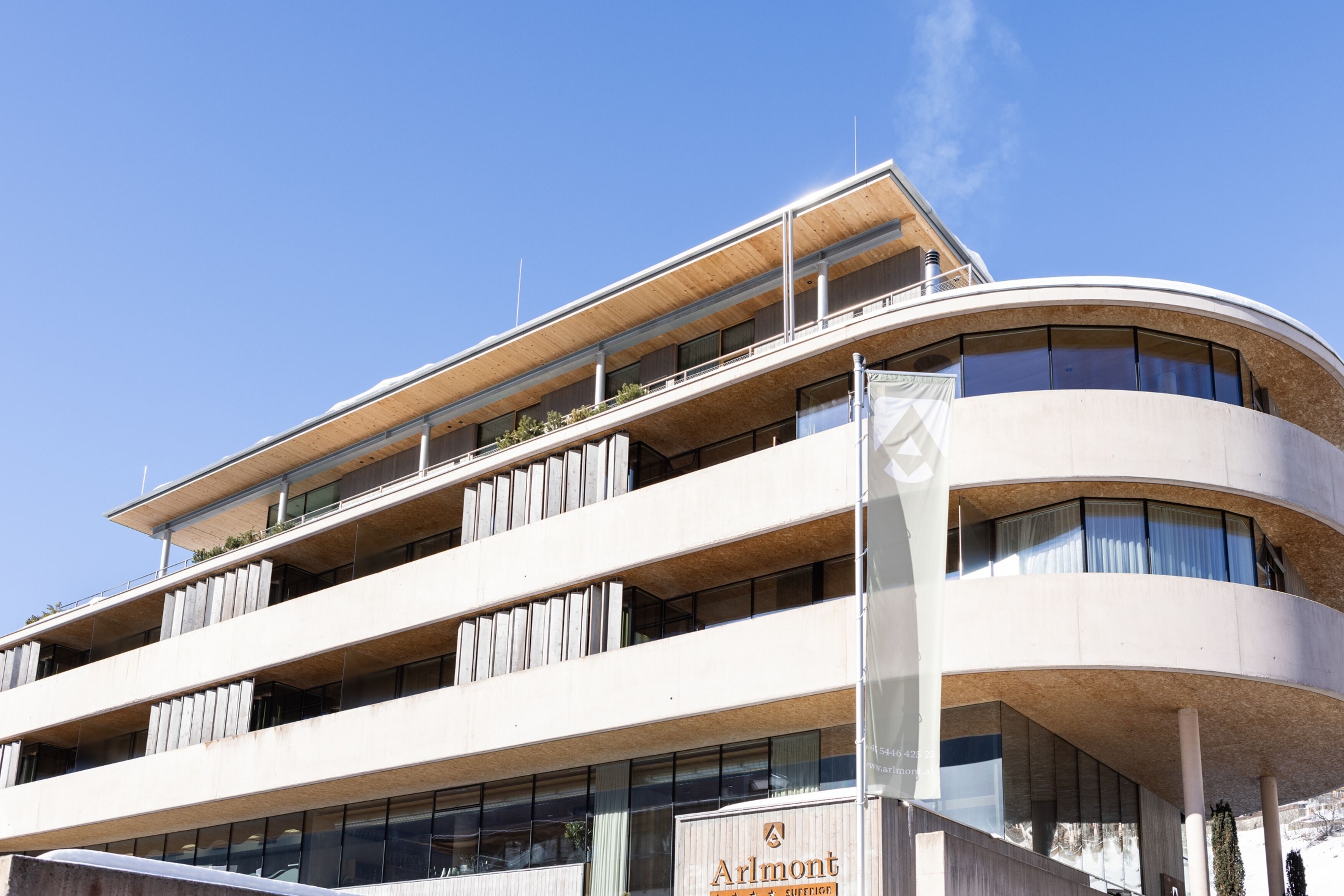 A modern multi-story building with a curved facade, large windows, and balconies.