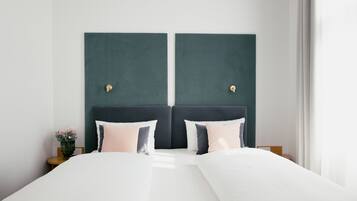 A double bed with a dark headboard, two bedside tables, and a vase with flowers on one side.