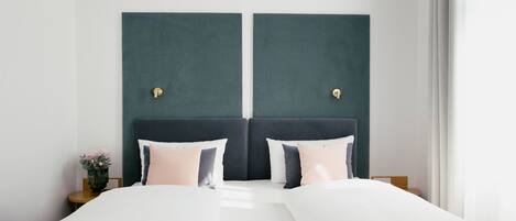 A double bed with a dark headboard, two bedside tables, and a vase with flowers on one side.
