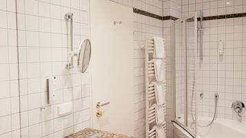 A modern bathroom with a granite countertop, a white sink, a glass shower enclosure, and a towel rack.
