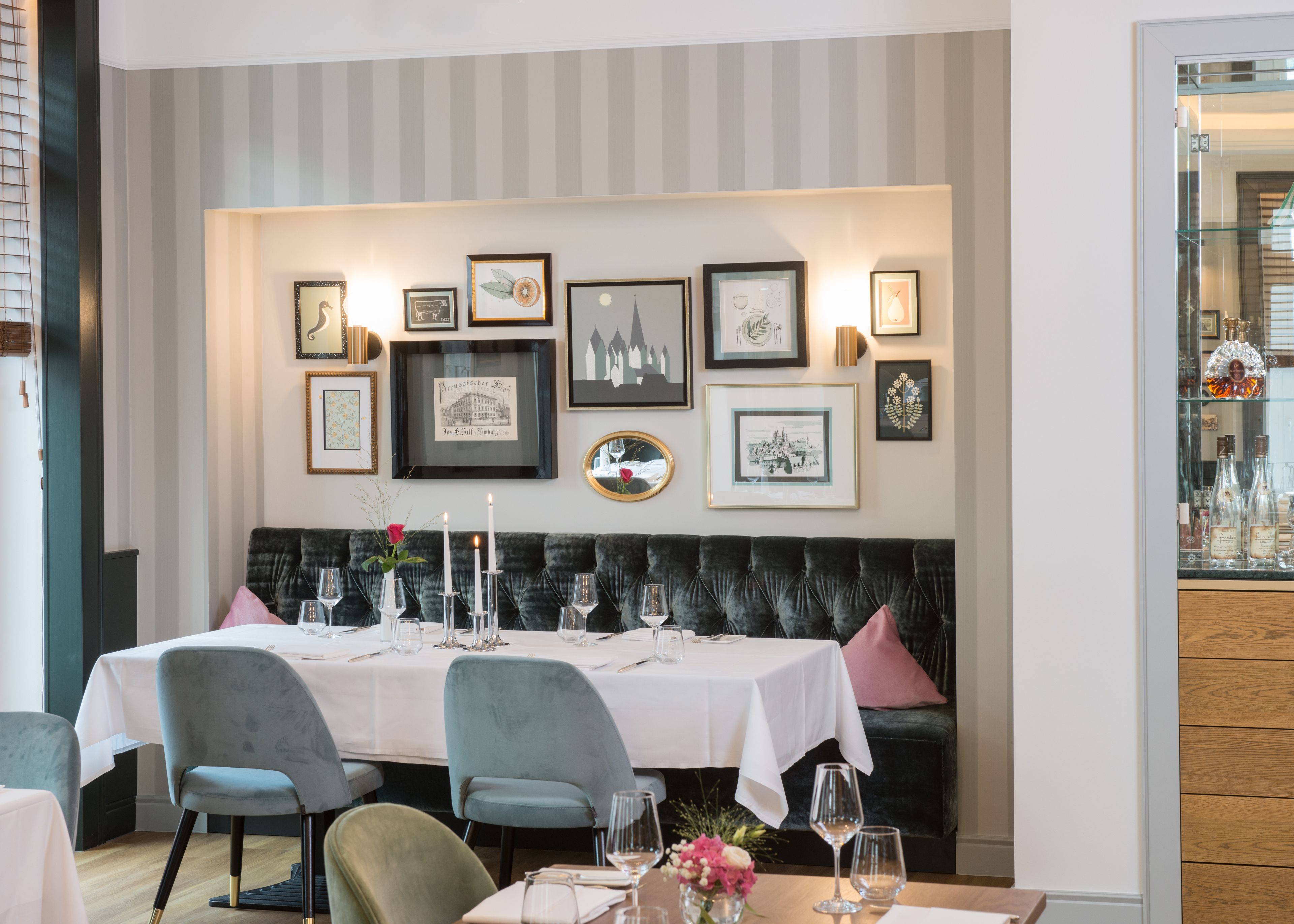 A dining area with a table set for four, a cushioned bench, and framed artwork on the wall.