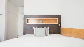 A neatly arranged hotel room with a bed, a bedside table, and a wardrobe.