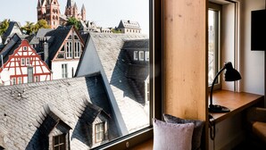A modern interior with a large window overlooking traditional European architecture. - Dom Hotel Limburg (Limburg an der Lahn)