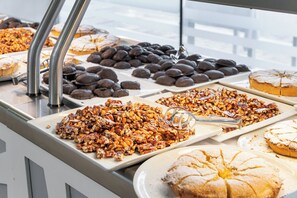 A buffet with various desserts including cakes, pastries, and a selection of nuts. - VOI Alimini Resort (Otranto)