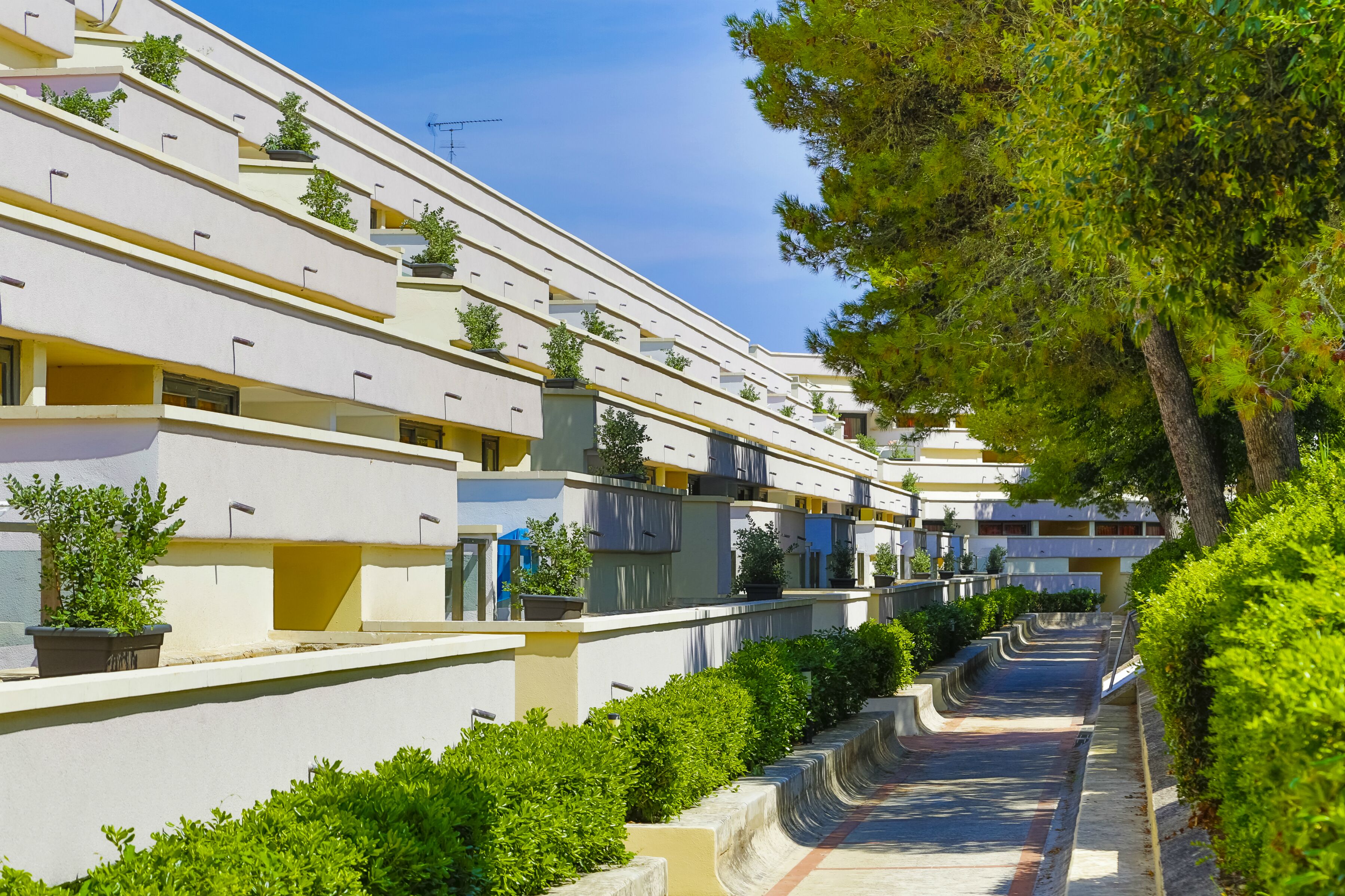 Un edificio moderno con numerosi balconi, ognuno decorato con piante in vaso.
