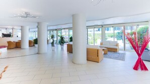 A spacious lobby with large windows, a modern chandelier, and comfortable seating areas. - Hotel King (Cervia)