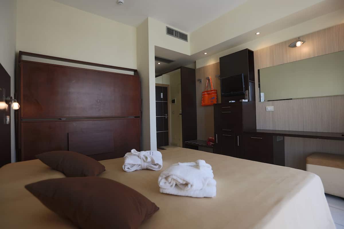 Ein Hotelzimmer mit einem großen Bett, einem hölzernen Kopfteil, einem Flachbildfernseher und einer Minibar.