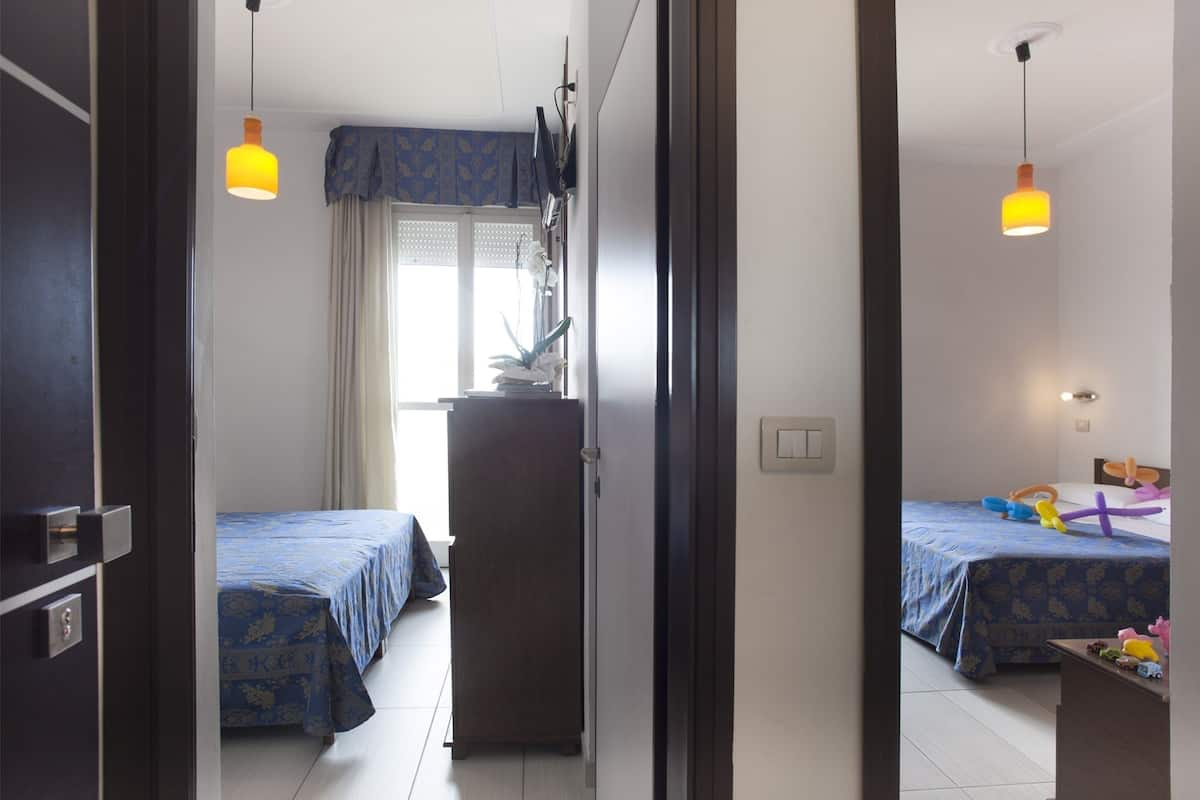 Ein Hotelzimmer mit zwei Betten, einem Kleiderschrank, einem Schreibtisch und einem Spiegel.
