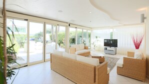 A spacious living area with a large sofa, a coffee table, and a flat-screen TV. There are sliding glass doors leading to an outdoor patio. - Hotel King (Cervia)