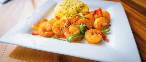 Un plato de camarones y verduras sobre un plato blanco.