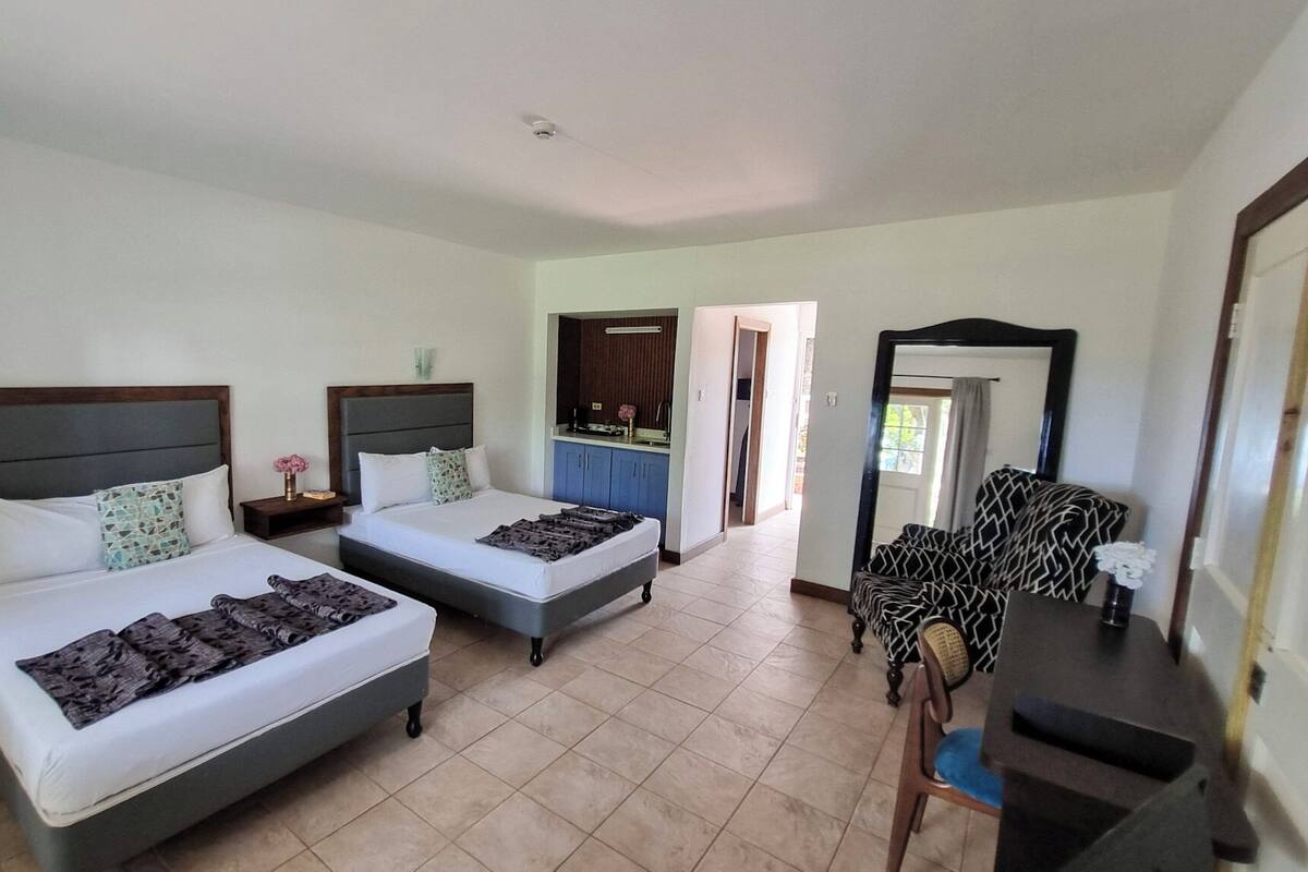 Une chambre d’hôtel avec deux lits, un bureau, une chaise et un miroir.