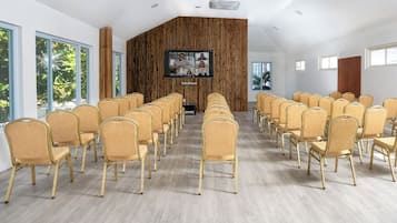 A conference room with rows of chairs, a large screen, and a wooden accent wall.