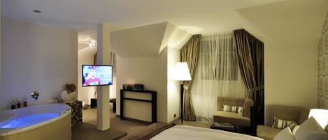 A hotel room with a large bed, a bathtub, a television, a desk, and a chair.
