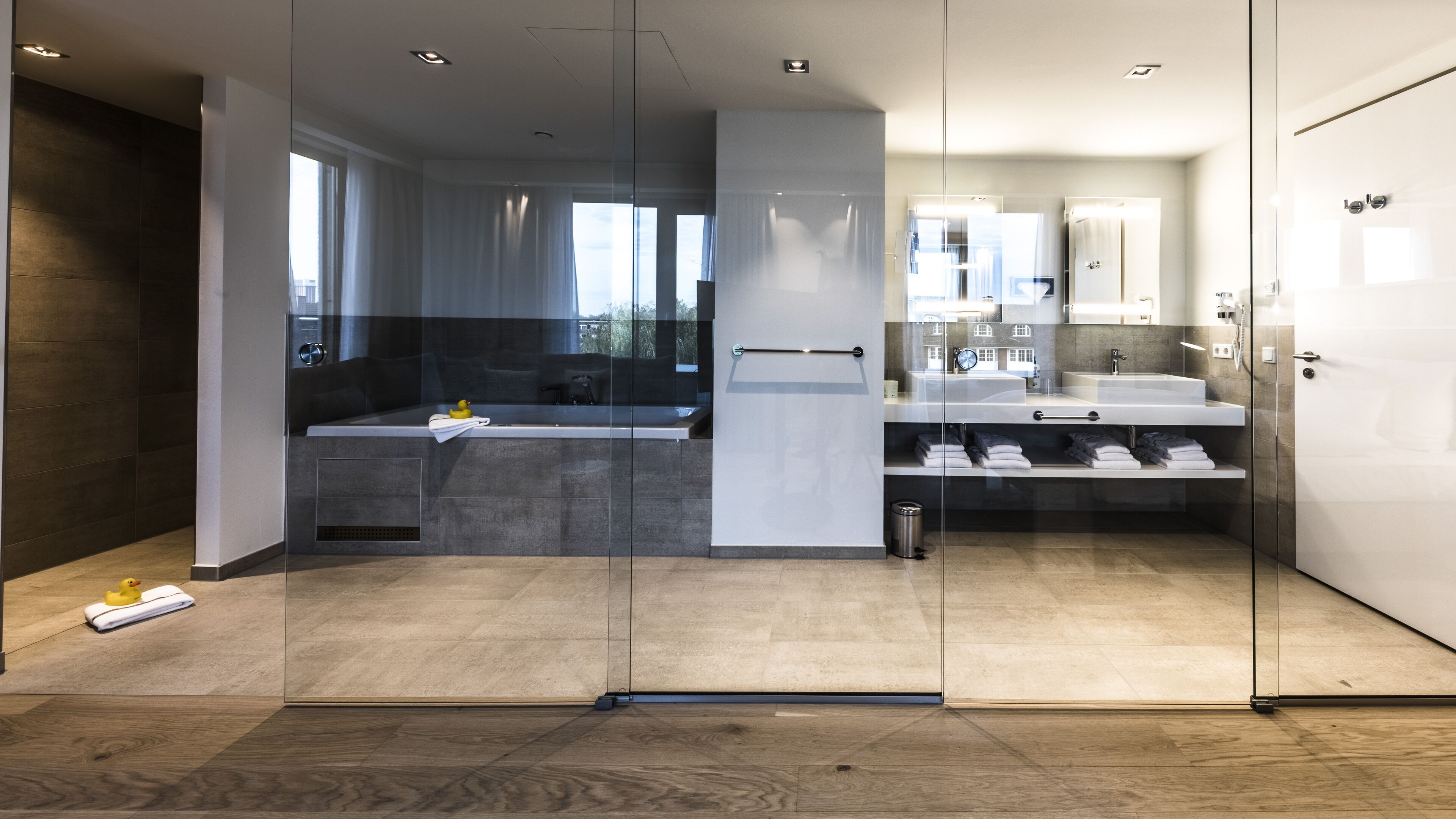 Un baño moderno con mampara de vidrio, bañera, zona de ducha y tocador con espejo.