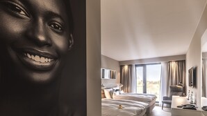 Una camera d'hotel moderna con un letto grande, una scrivania e un balcone con tende.