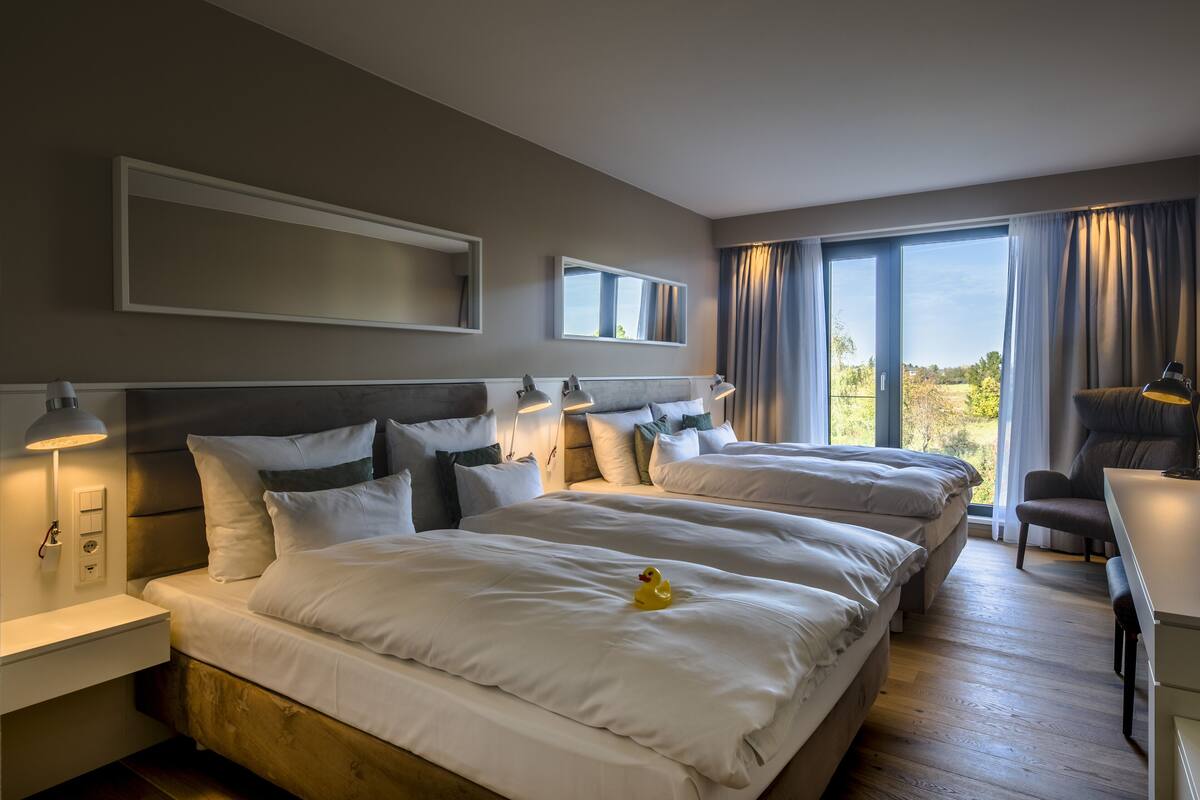 Een hotelkamer met twee bedden, een bureau en een stoel.