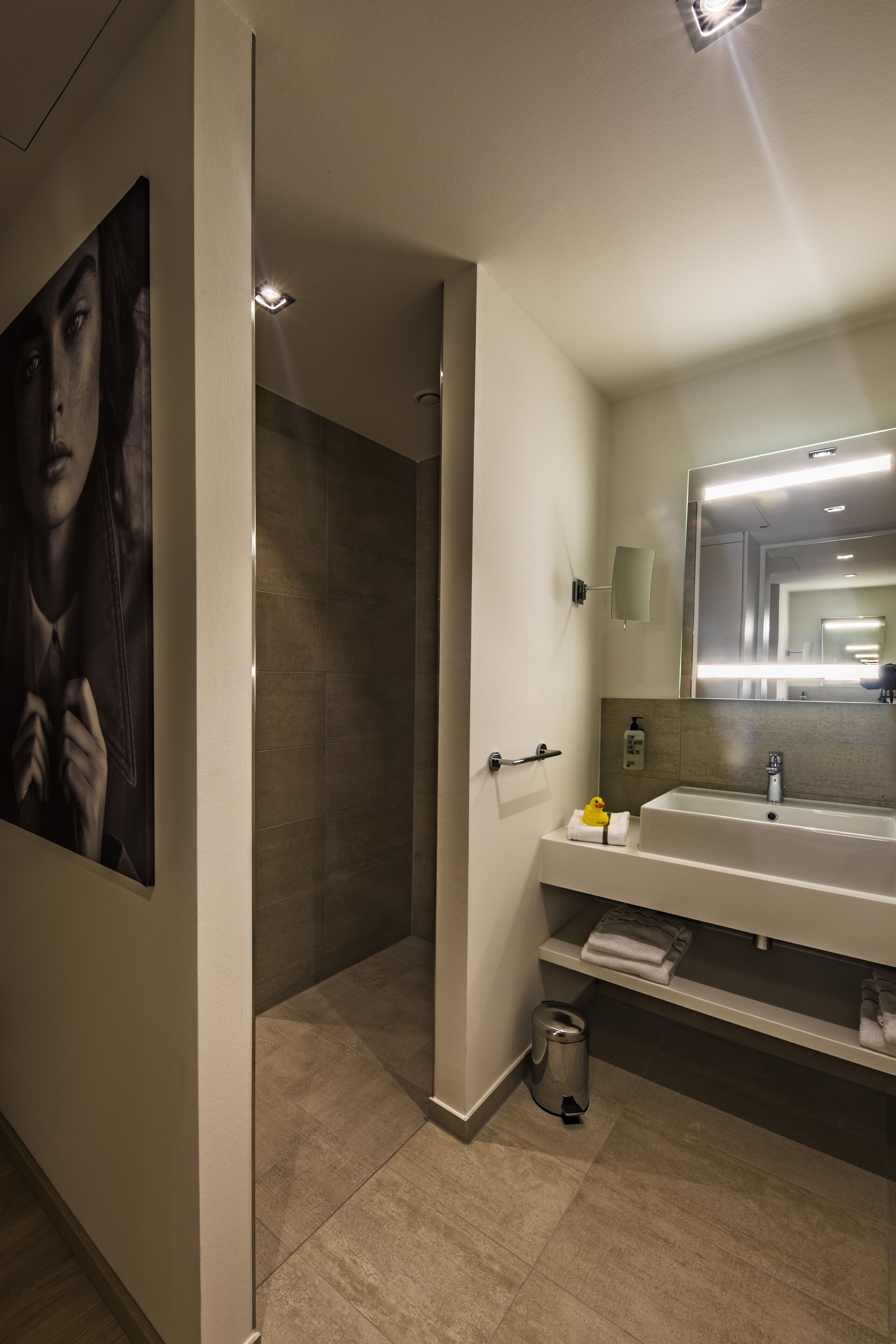 A modern bathroom with a large mirror, a sink, and a shower.