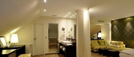Una habitación de hotel moderna con una cama grande, una zona de estar con sofá, un baño independiente con bañera y un comedor con mesa y sillas.